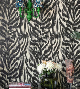 A close-up of Zebrato Nero wallpaper by Mind The Gap, paired with a vibrant green wall sconce, fresh flowers, and eclectic decorative accents