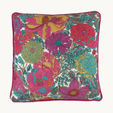 Photo of a bright colourful floral cushion with retro inspired flowers in hot pink, grape, bright turquoise, coral and orange.