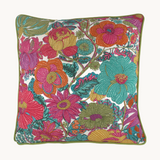 Photo of a bright colourful floral cushion with retro inspired flowers in hot pink, grape, bright turquoise, coral and orange with caper green piping