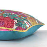 Side view of a bright colourful floral cushion with retro inspired flowers in hot pink, grape, bright turquoise, coral and orange with gold piping and a turquoise cotton back
