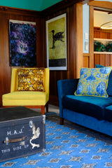 Photo of a colourful living room with a bright yellow chair and bright floral cushion