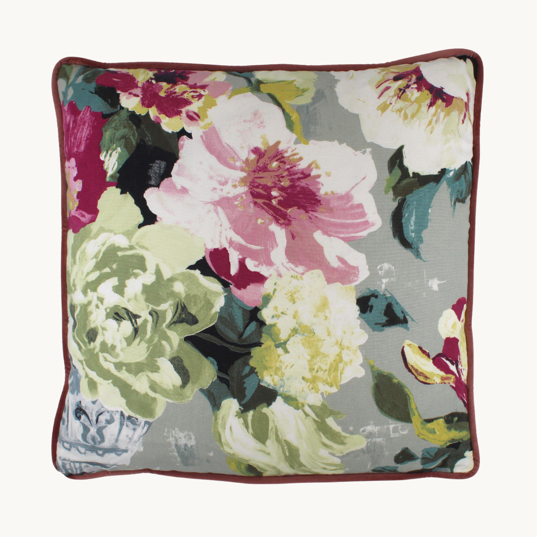 Photo of a cushion in a floral with a light grey background and large scale blooms in pink, magenta and very pale green