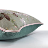 Side view of a cushion made from a vintage linen with a whimsical floral boquet of roses in soft pinks, duck egg blue and sage green with baby pink velvet piping