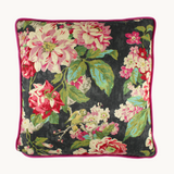 Photo of a cushion in a bright floral design with a charcoal base and bright pink, green and aqua roses and leaves