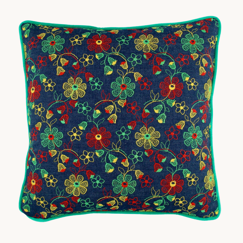 Photo of a vintage floral embroidered cushion, a denim base cloth with naive red, yellow and spearmint green flowers