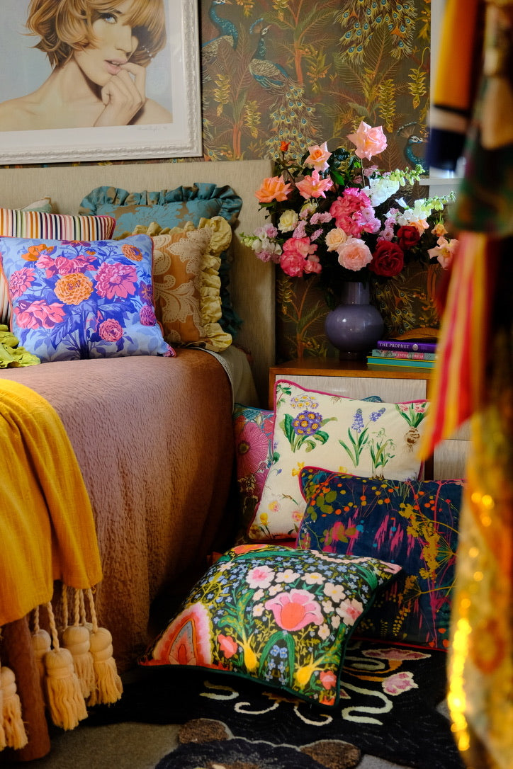 Decorative bedroom room with colorful cushions and flowers on the bedside.