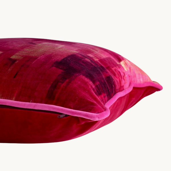 Side shot of a vibrant pink velvet cushion with velvet piping