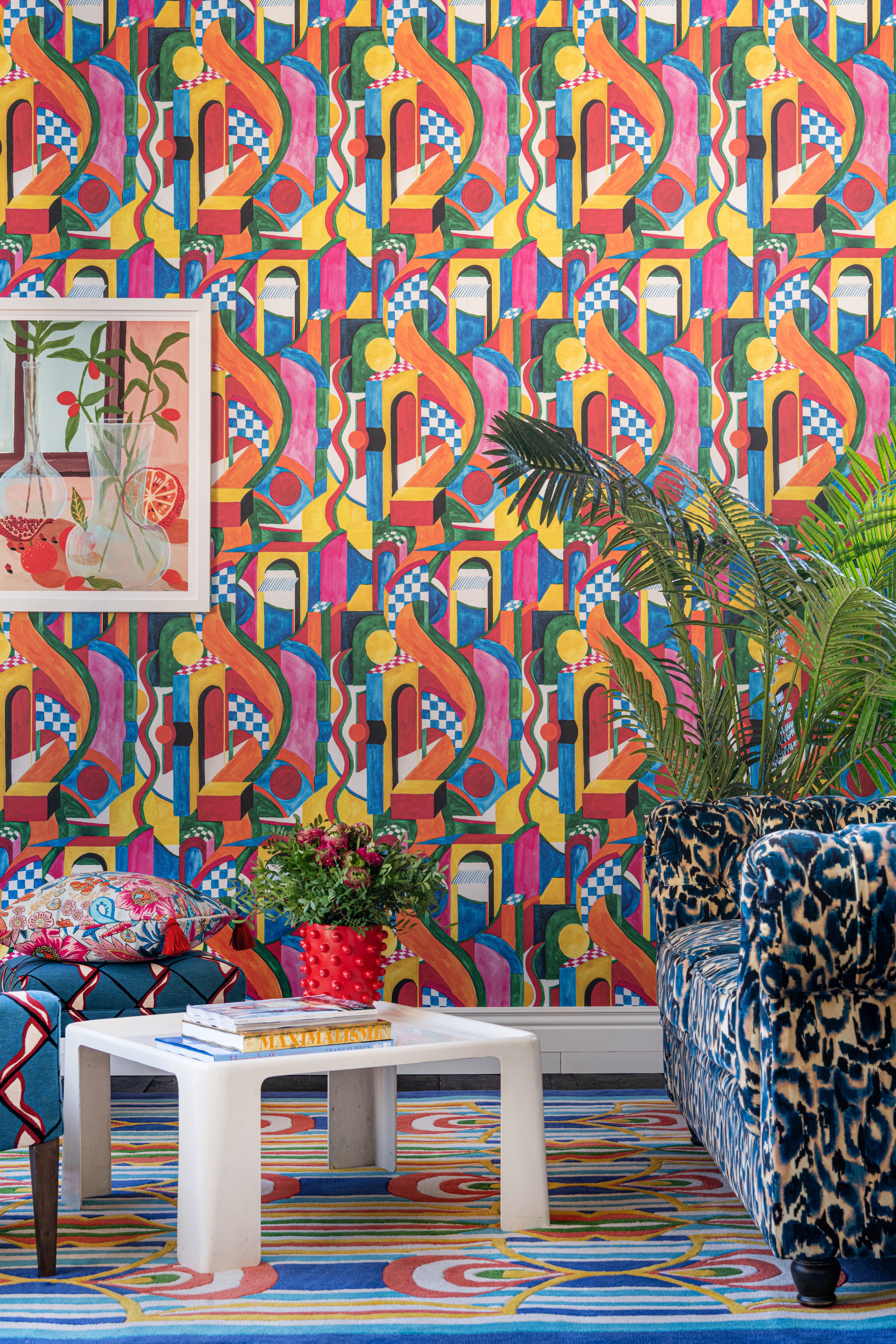 Room with vibrant BOSSA NOVA wallpaper, bold geometric patterns, a plush blue leopard print sofa, colourful accents, lush greenery, and eclectic decor.