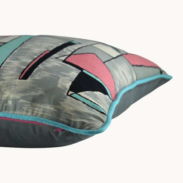 Side shot photo of a cushion with a geometric design in grey, pink and aqua