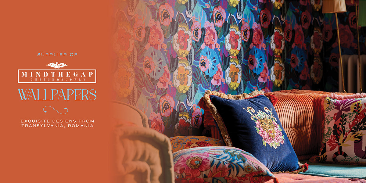 Colorful floral wallpaper with a sofa and pillows in a room setting, featuring Mindthegap Wallpapers branding.