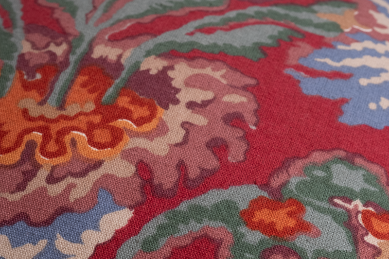 Close-up of a colorful floral patterned fabric with red, green, and orange colors.