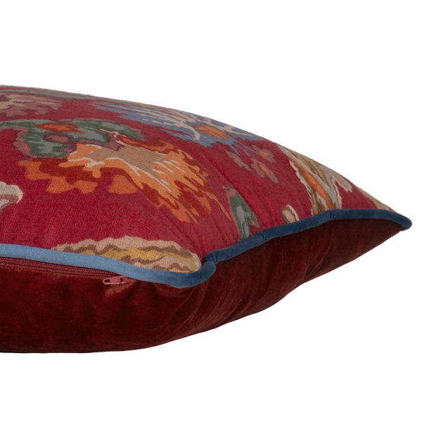 Side shot of a linen cushion in a rich red with blue and green large scale scrolled design