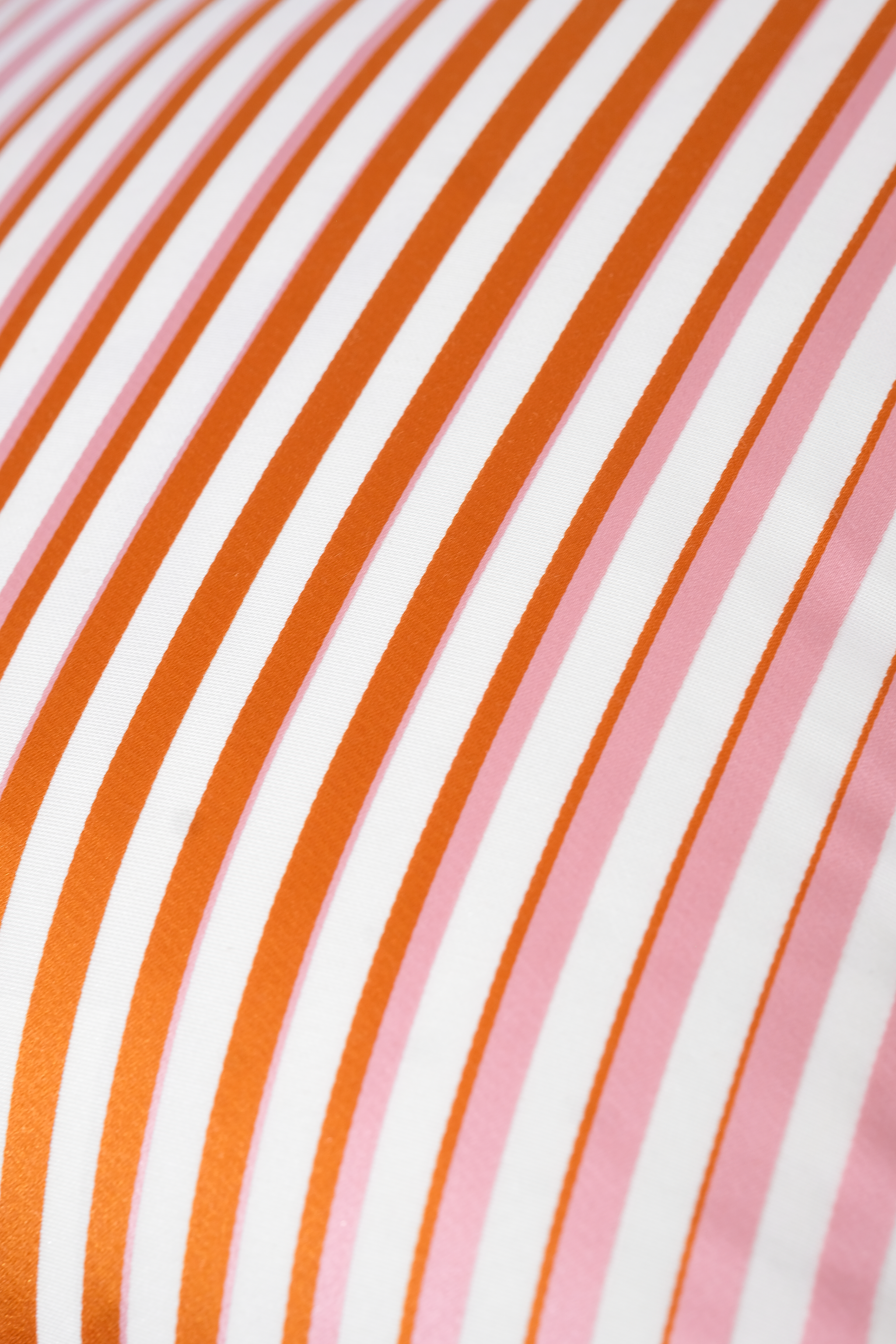 Close-up of fabric with orange, white, and pink stripes.
