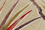 Close-up of fabric with red, brown, and beige large scale strappy leaves pattern