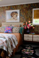 Bedroom with a large floral arrangement, peacock wallpaper and lots of decorative elements