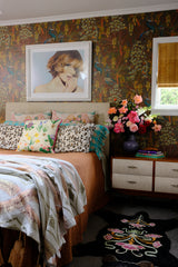 Bedroom with a large floral arrangement, peacock wallpaper and lots of decorative elements