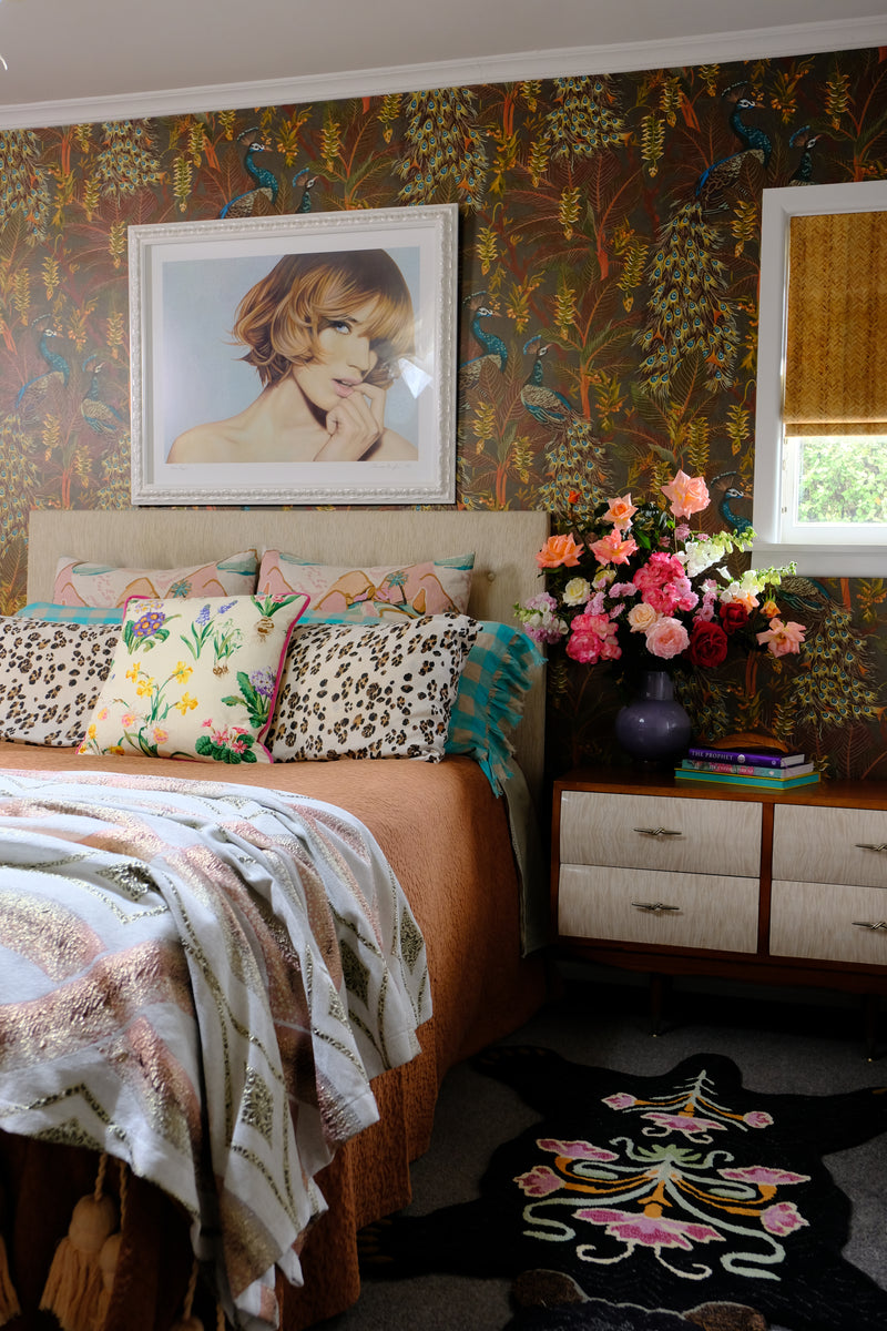 Bedroom with a large floral arrangement, peacock wallpaper and lots of decorative elements