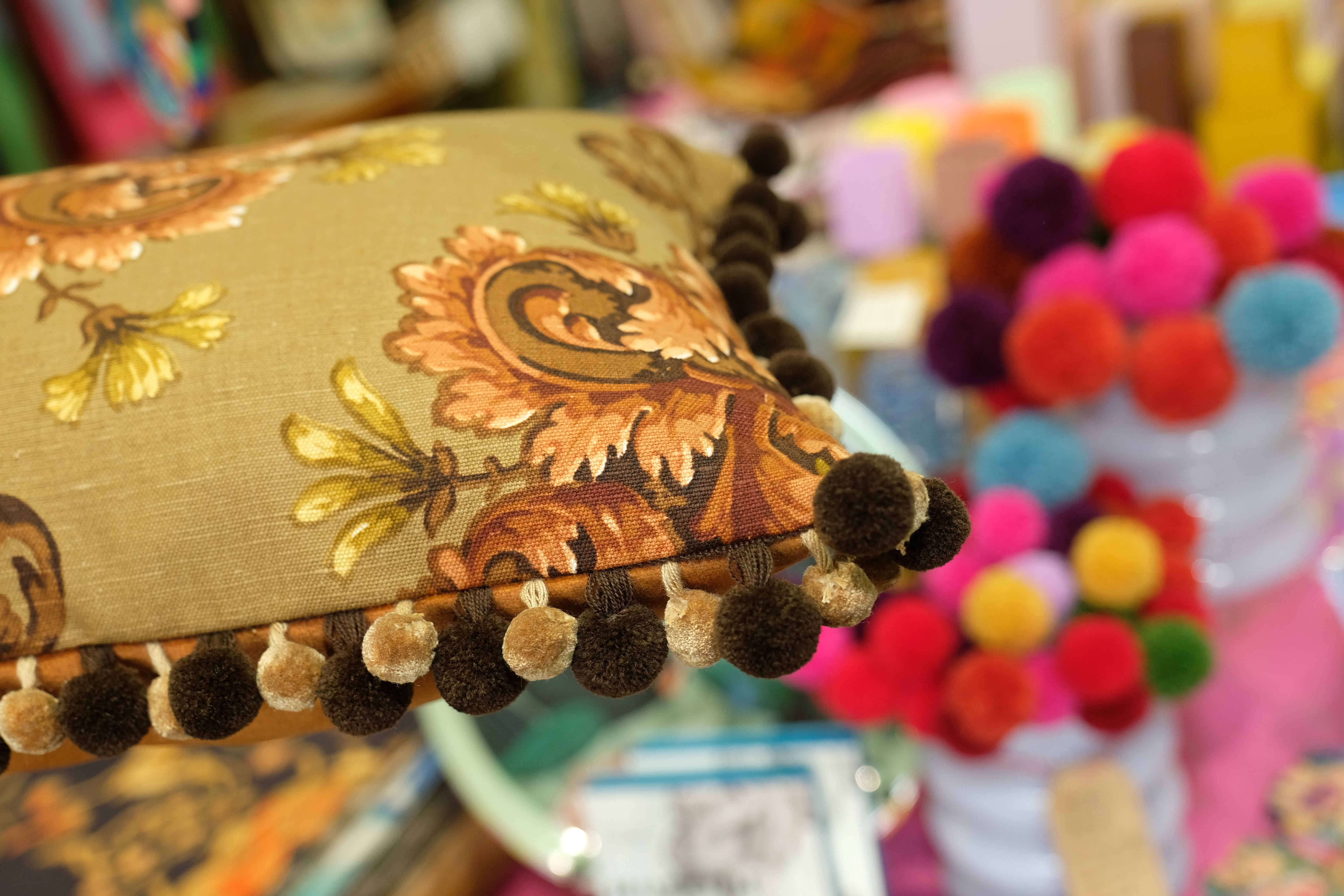Decorative pillow with pom-pom trim on a colorful background