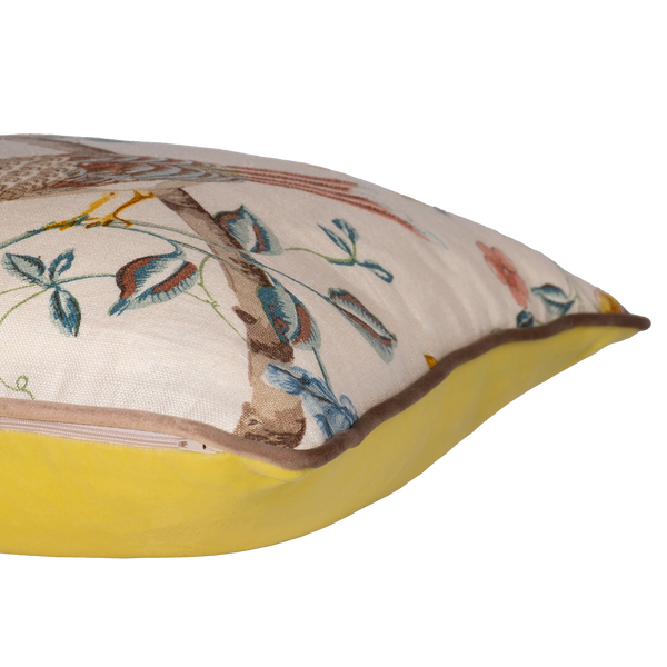 Side view of a decorative cushion with floral and bird design on a linen background