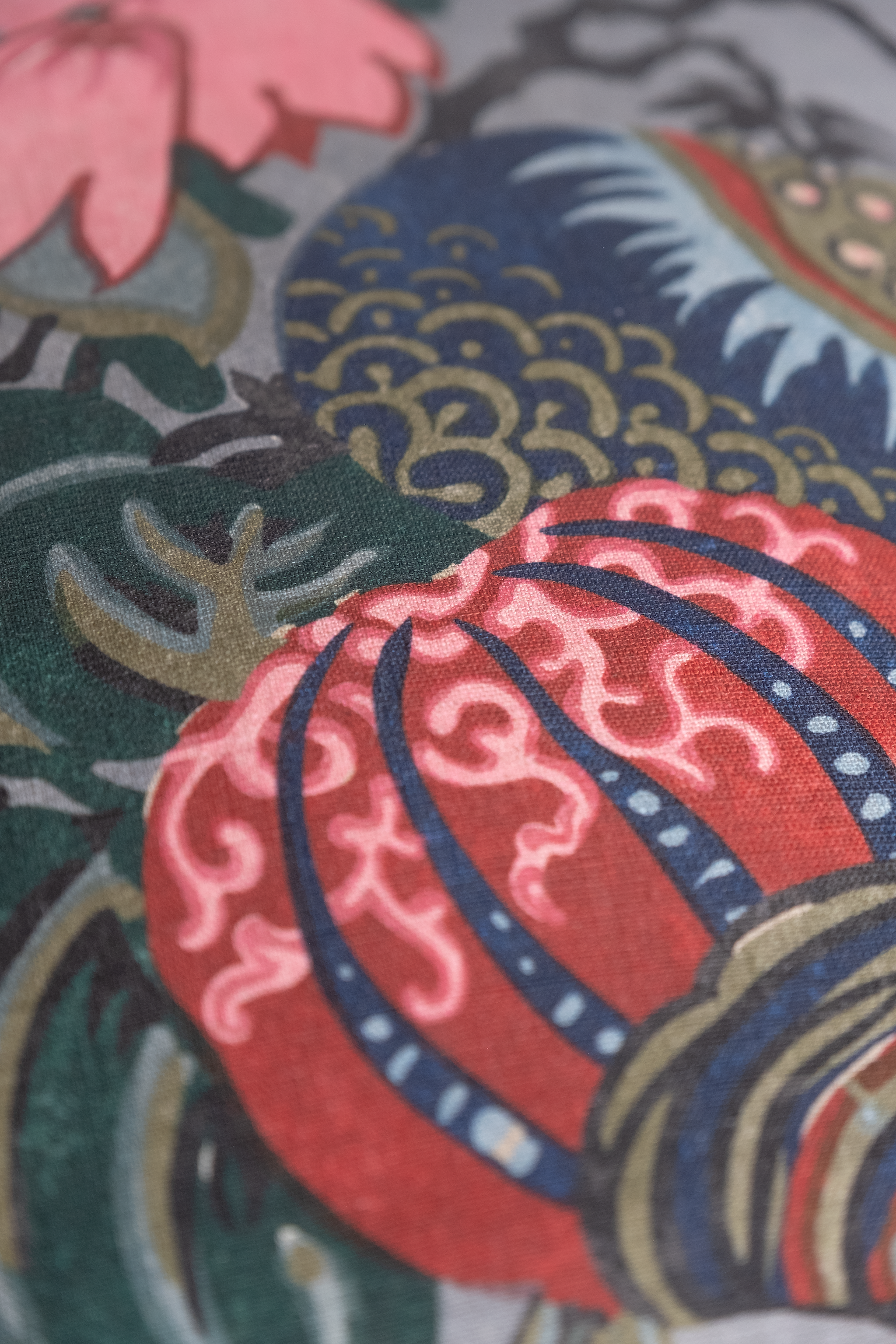 Close up of a floral linen featuring flowers in grey pink red navy and aquamarine.