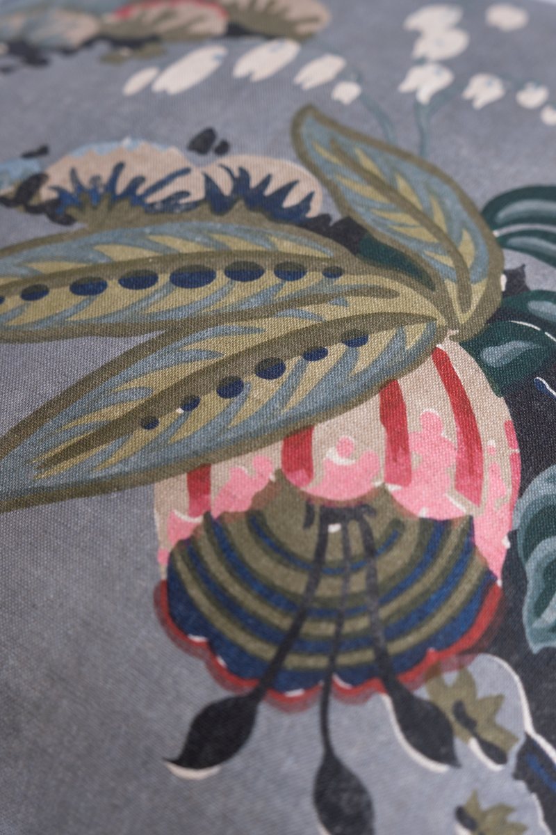 Close up of a floral linen featuring flowers in grey pink red navy and aquamarine.