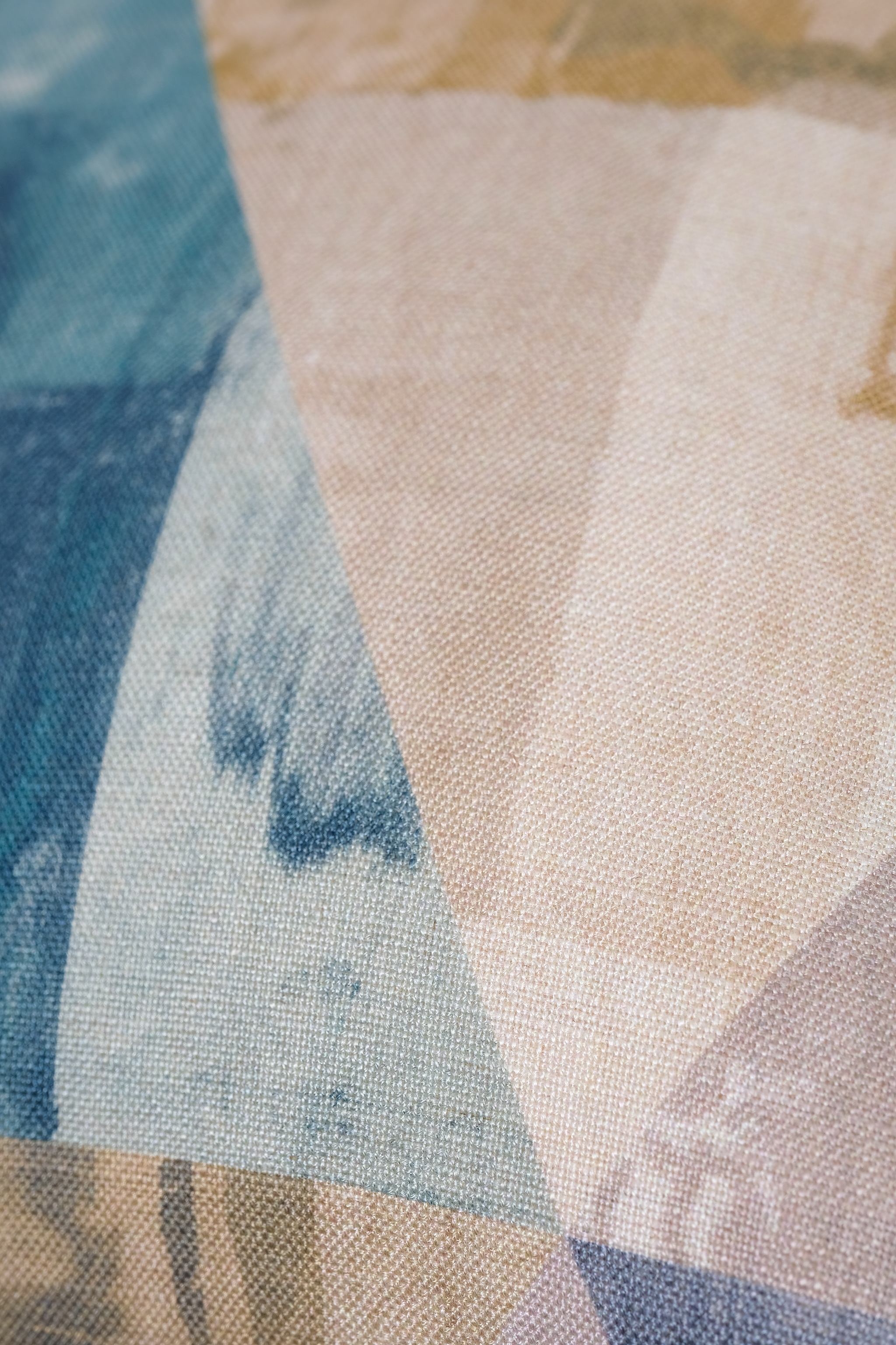 A close-up of a fabric with a geometric abstract print featuring blocks of blue, beige, and light gray.