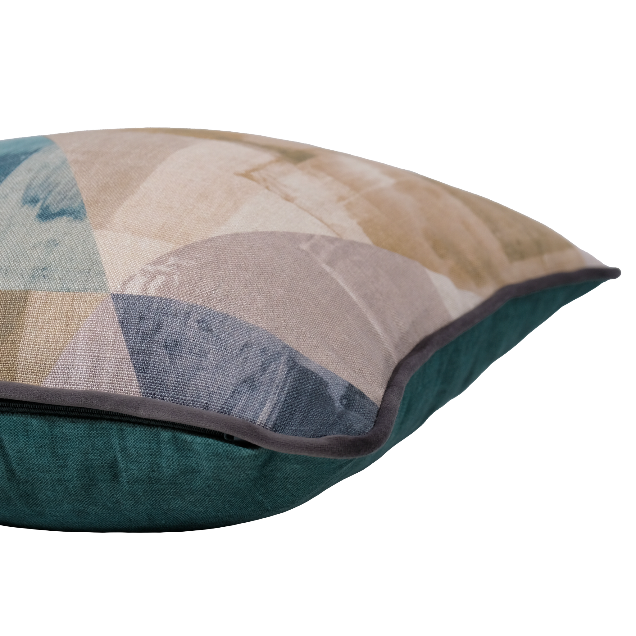 A close-up of a decorative throw pillow showing a geometric patchwork pattern in beige, blue, and gray on the front, with a dark teal velvet reverse side and dark piping.