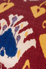 Close up of an ikat patterned fabric in a deep russet colour with navy and yellow accents