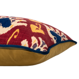 Side of a cushion with an ikat pattern in a deep russet colour with navy and yellow accents and gold velvet on the back