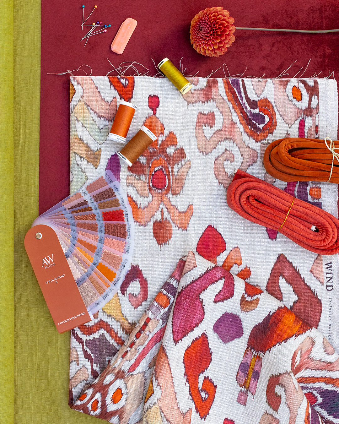 Color swatch book with fabric swatches and sewing supplies on a red background