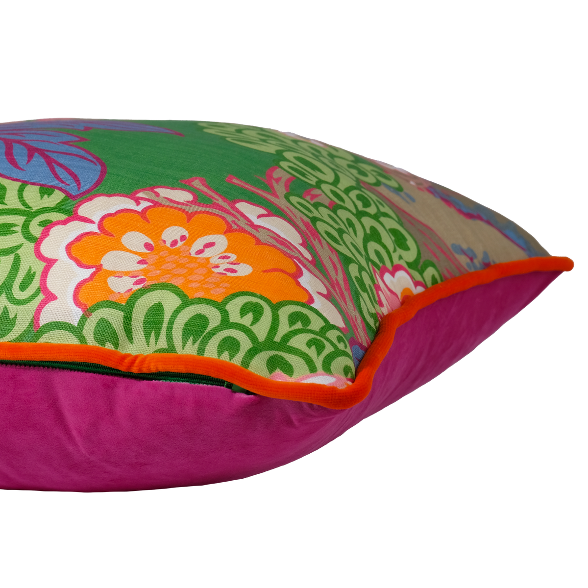 A square decorative throw pillow with a vibrant multicolor floral and botanical print on one side and a bright magenta velvet reverse side with an orange piping edge, isolated on a white background.
