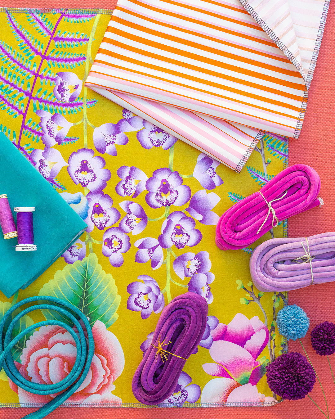 Colorful fabric samples with floral patterns and sewing supplies on a vibrant background