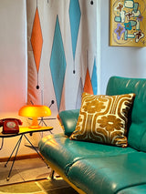 photo of a retro floral cushion on a teal leather sofa.