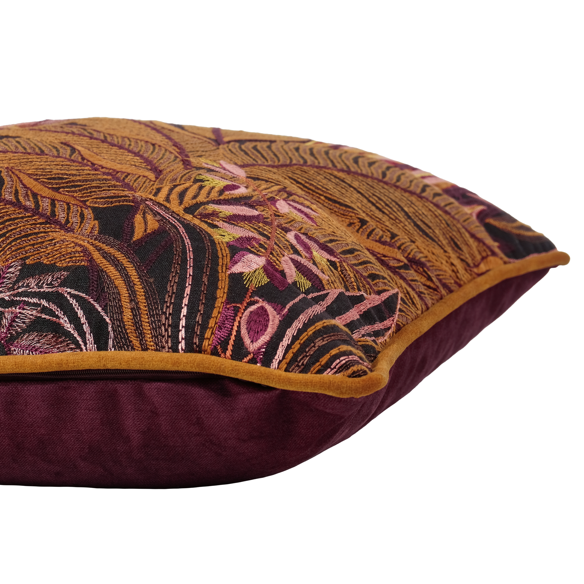 A close-up of a decorative throw pillow featuring a detailed botanical tapestry pattern in gold, black, and pink, with a solid deep burgundy velvet reverse side and a gold piped edge.