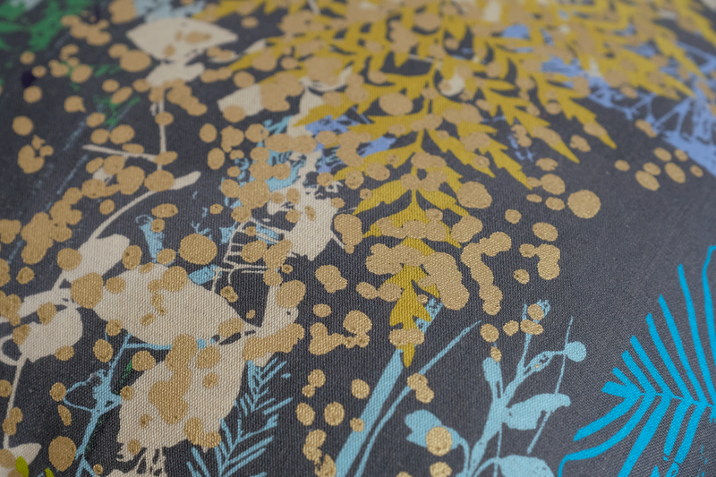 Close up of a printed fabric with botanical silhouettes in multiple colours on a grey background
