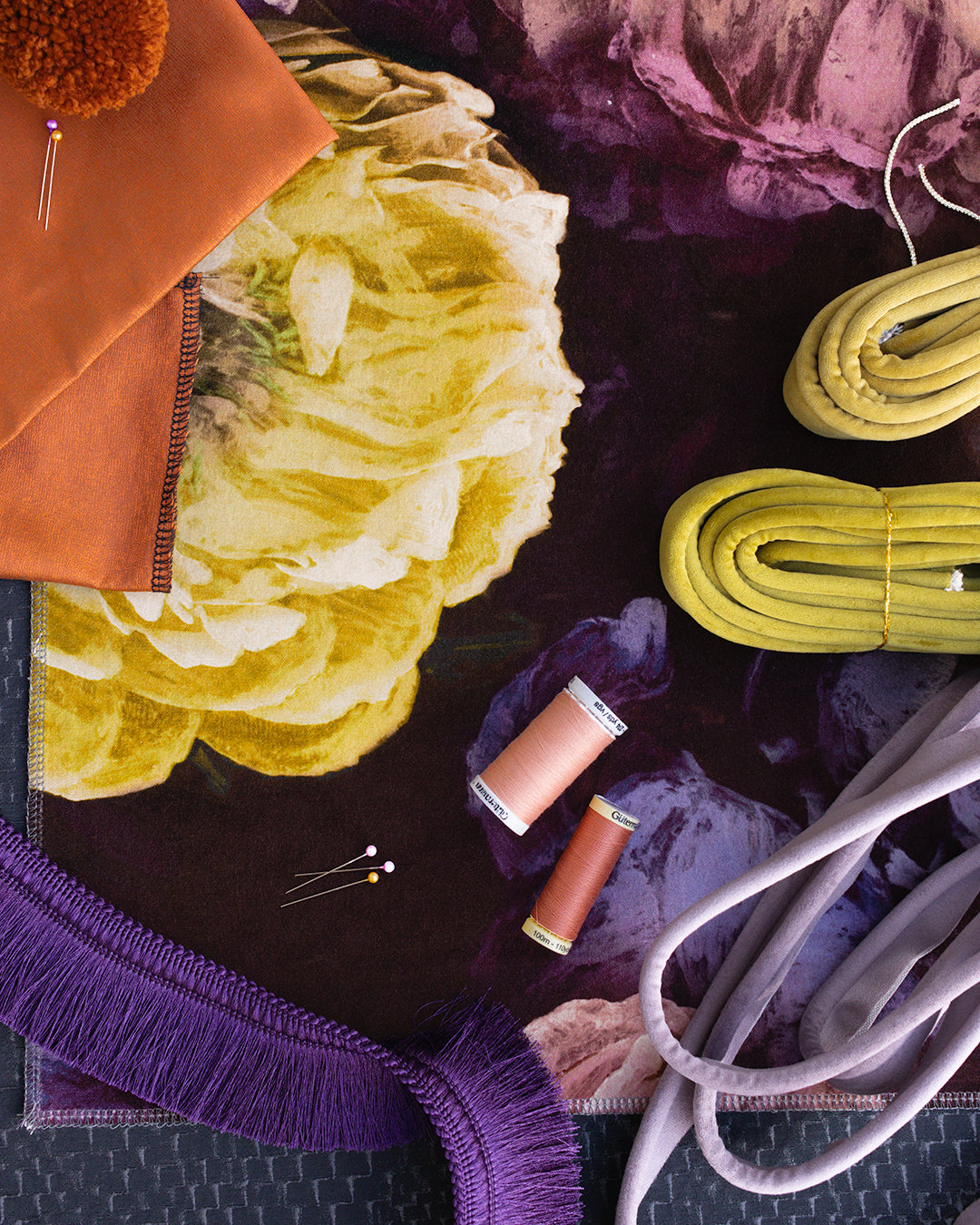 Colorful fabric swatches and sewing materials on a dark surface