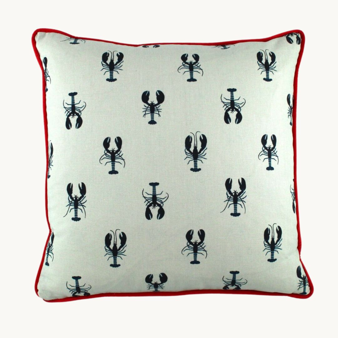 Photo of a cushion with small inky navy lobsters printed onto a white linen with a bright red velvet piping