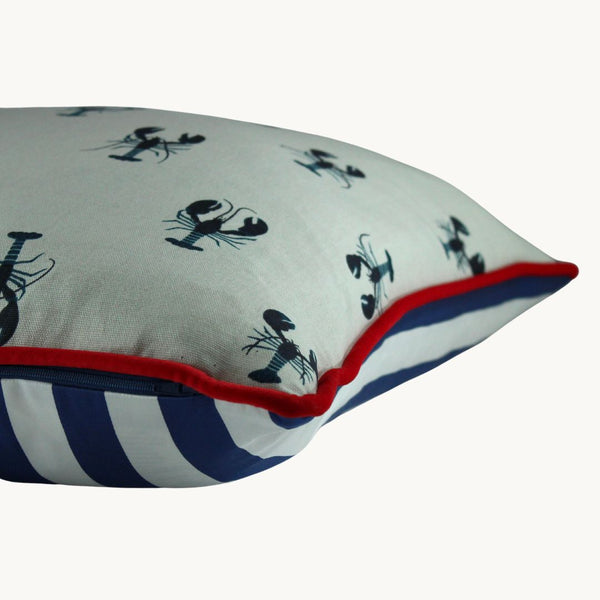 Side photo of a cushion with small inky navy lobsters printed onto a white linen with a bright red velvet piping