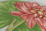 Close-up of a fabric showing a pink flower with green leaves on a light blue background
