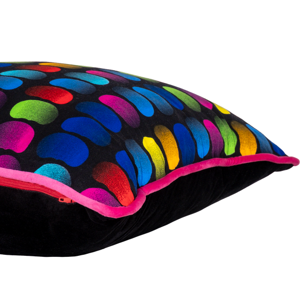 Side view of a neon bright cushion with rainbow of coloured beans on a black background