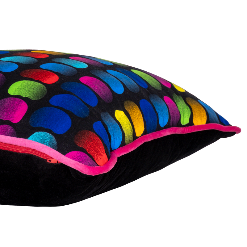 Side view of a neon bright cushion with rainbow of coloured beans on a black background