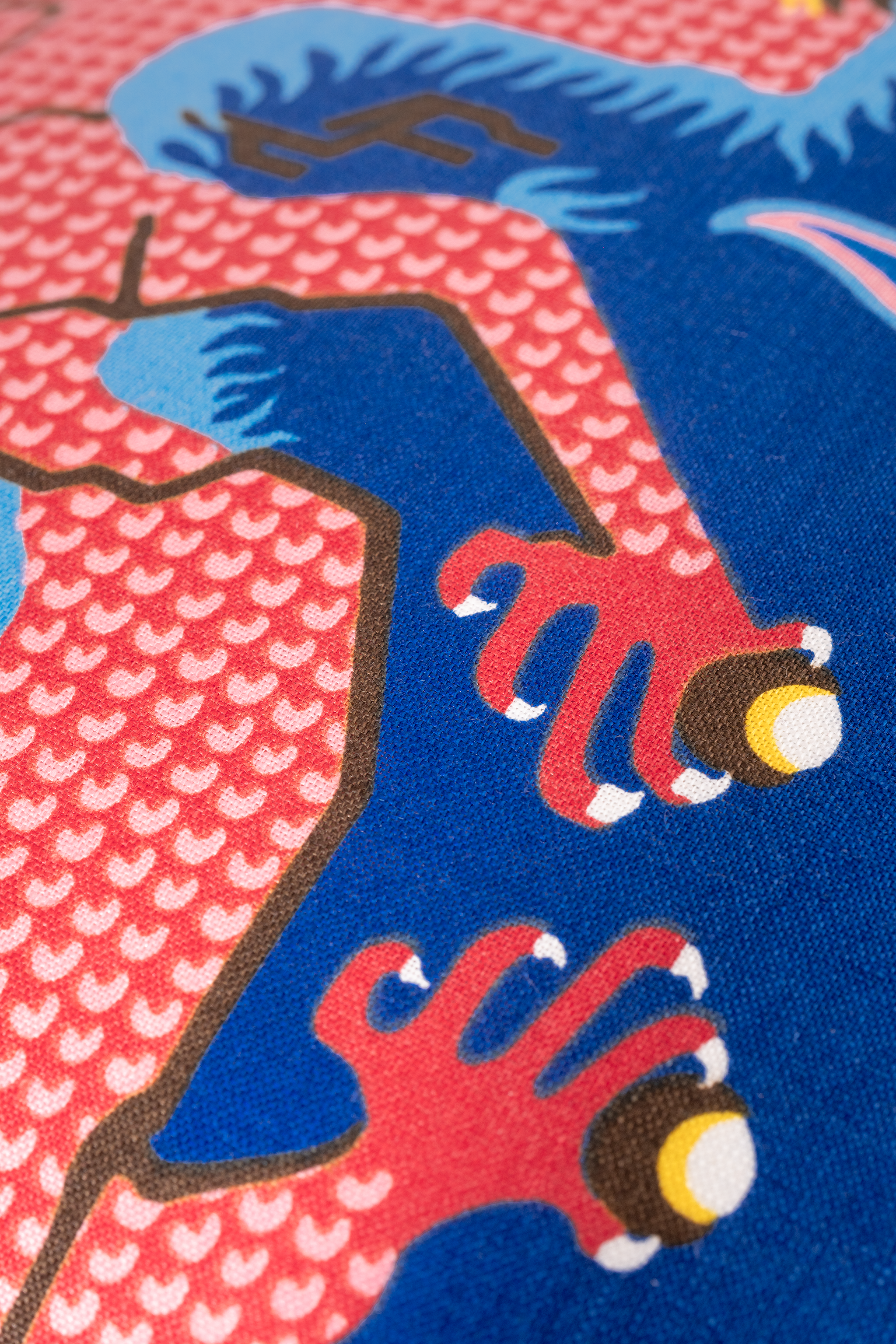 Close-up of a colorful dragon design with blue, red, and yellow elements on a textured background.