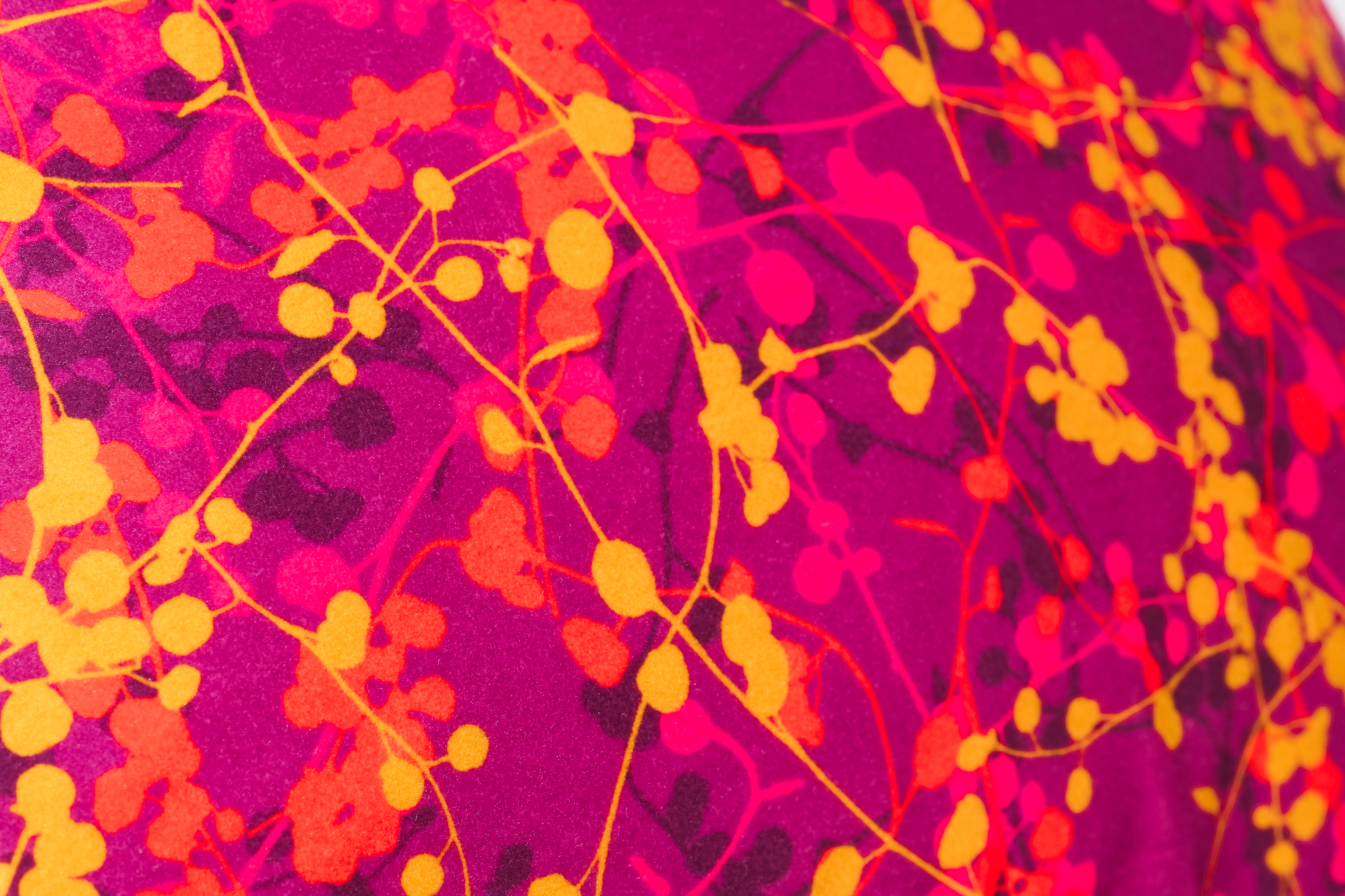 Close-up of a vibrant fabric with pink, orange, and yellow leafy pattern