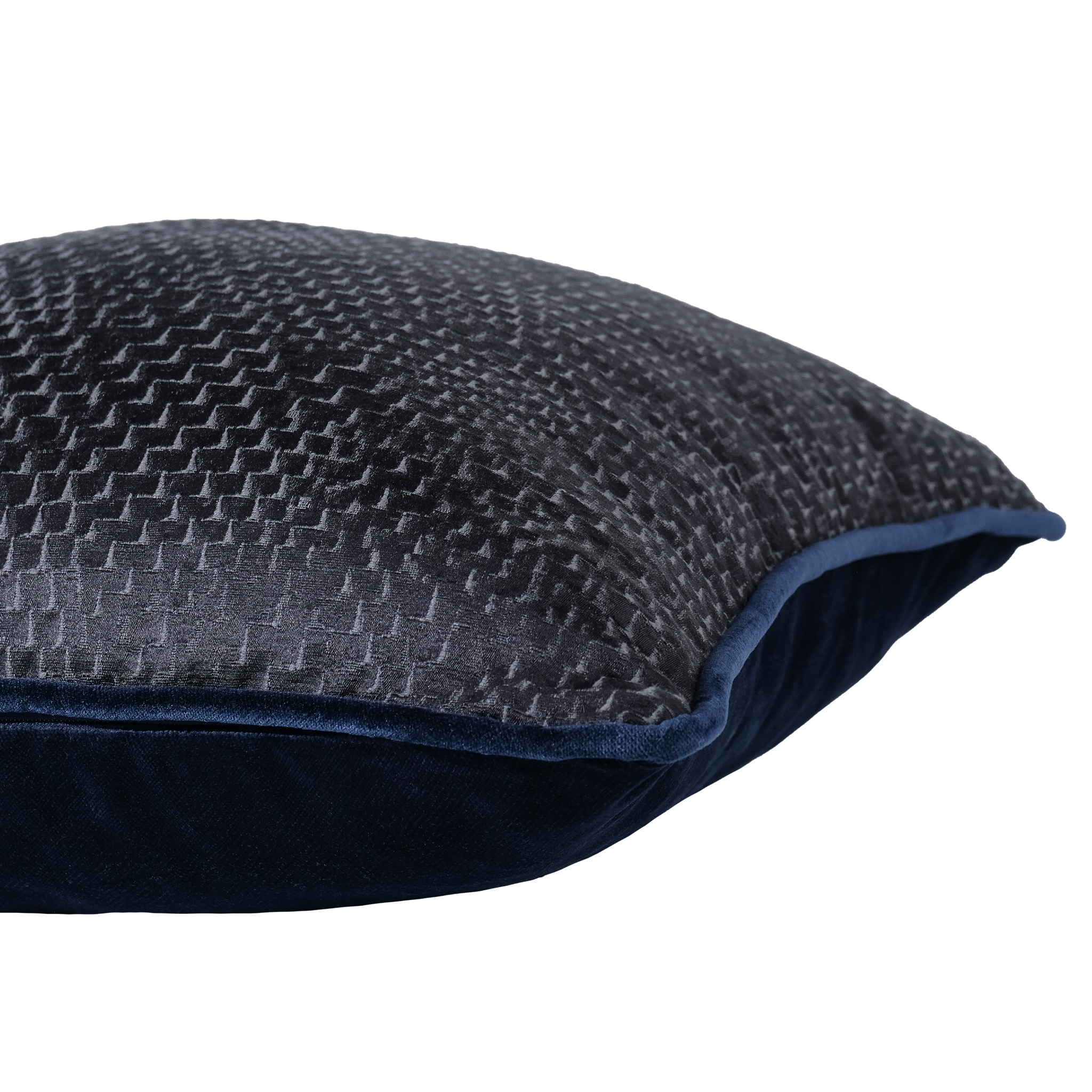 A close-up of a dark charcoal gray textured throw pillow with a navy blue velvet edge and solid navy blue underside