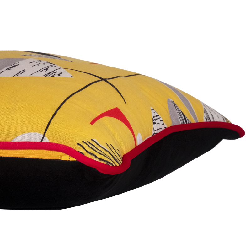 Side view of a colourful cushion made from a vintage fabric with geometric shapes on a bright yellow base.