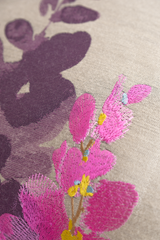 Close-up of embroidered pink flowers with green leaves on a fabric background