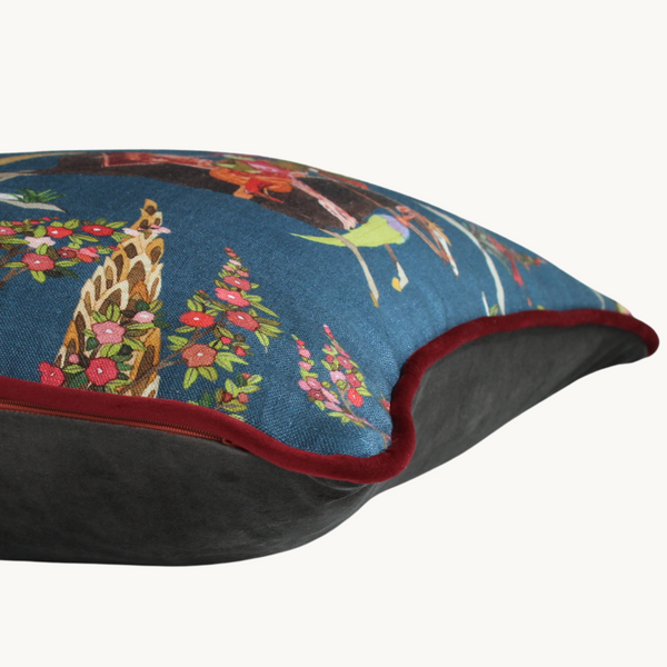 Side shot of a linen cushion with a printed design featuring Ottoman Riders and flowers on a blue background