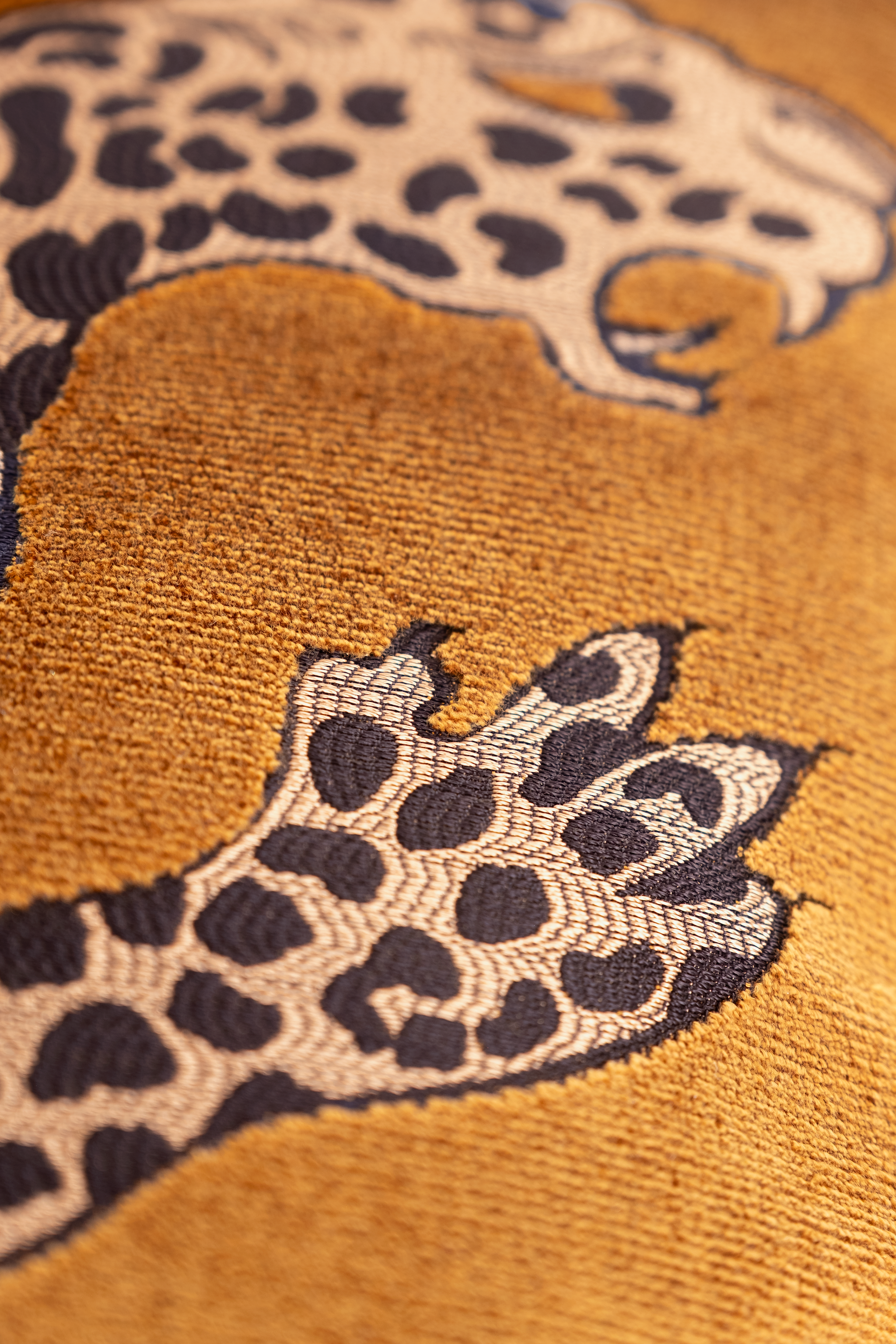 Close-up of embroidered leopard pattern on gold velvet fabric 