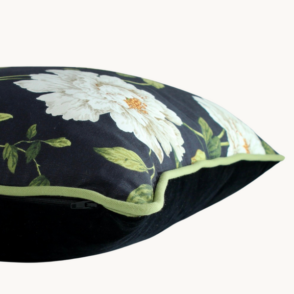 Side shot of a cushion with a black background and white peony flowers with green foliage
