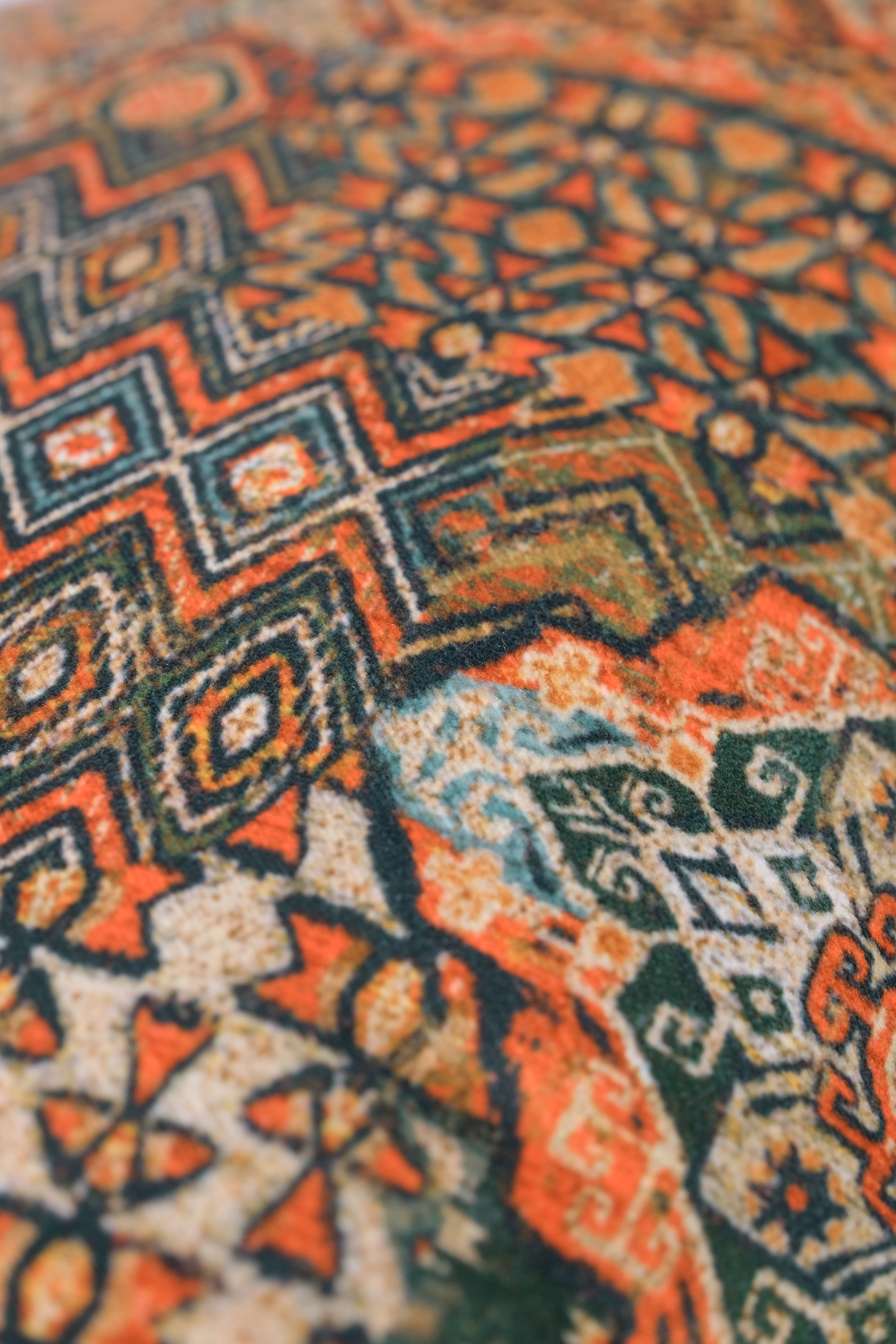 Close-up of a Persian patterned velvet with geometric designs in orange, green, and caramel